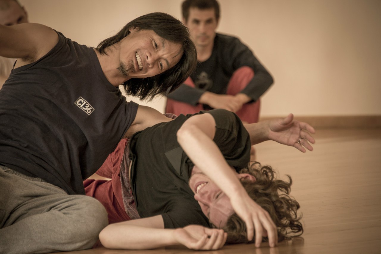 Artem dancing on the floor, someone laughing and moving over him